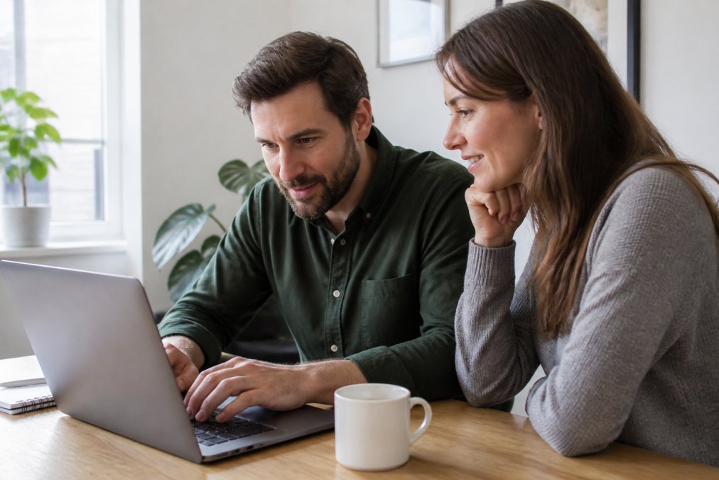 Een website-eigenaar achter een laptop met een beveiligingsdashboard op het scherm, in een rustige kantooromgeving met natuurlijk licht
