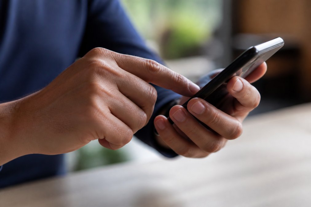 Close-up van hand die op duidelijke, groene call-to-action button klikt op smartphone-scherm, met focus op de vingerbeweging en button-contrast
