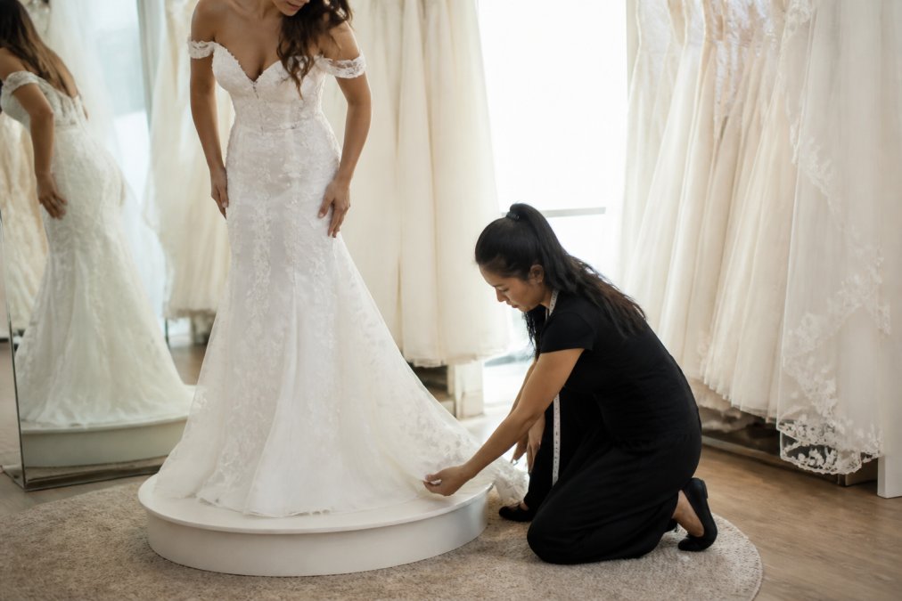 Professional illustration showing bride and standing and fitting concepts for wedding dress alterations cost