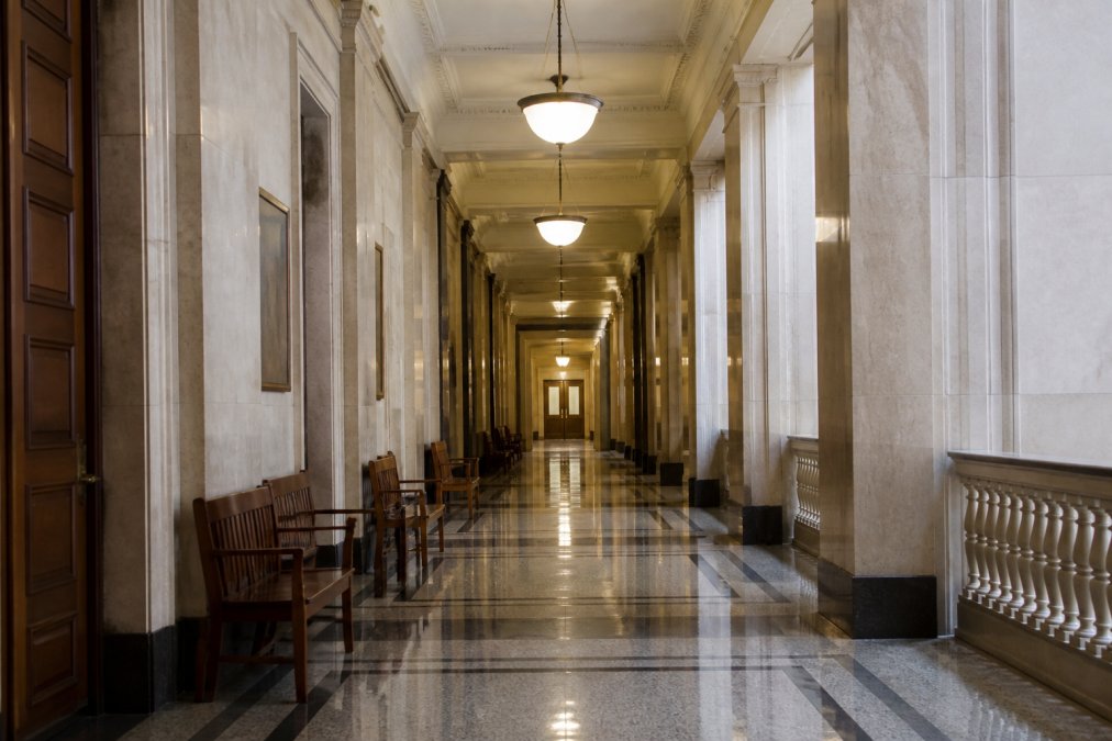 Interior of a modern courthouse hallway with professional architectural details, polished floors, and dignified lighting that conveys judicial authority and the formal atmosphere of legal proceedings