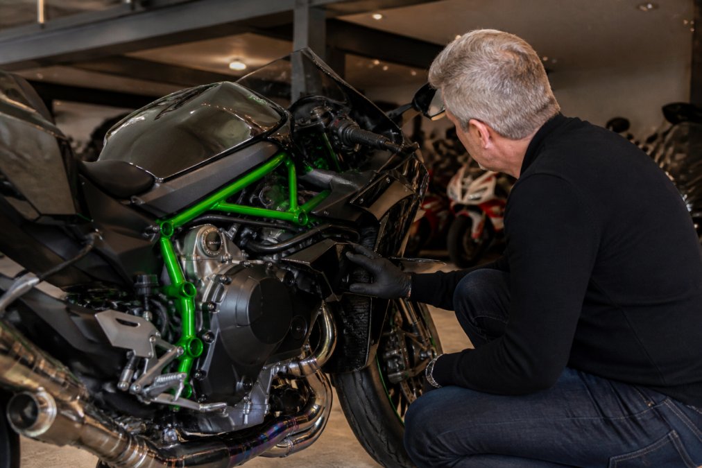 Verzamelaar bekijkt een glimmende sportmotor in een moderne garage met uitstekend zicht op het motorblok.
