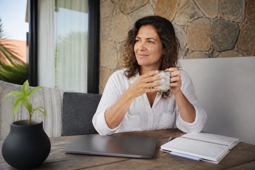 Professional coach sitting at desk with laptop closed, calendar visible, looking calm and focused during a scheduled break