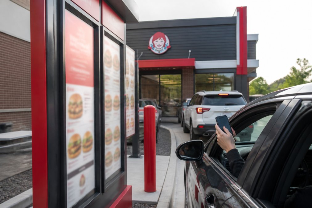 Customer using a mobile app at a digital Wendy’s drive-thru, highlighting trends in franchisee economics.