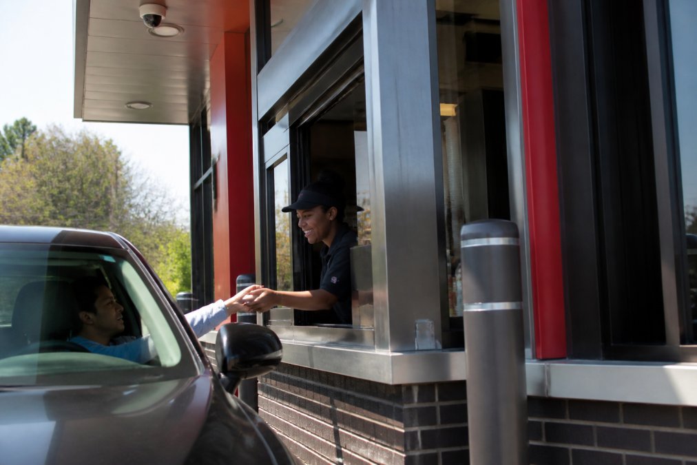 Modern Wendy's drive-thru window with digital menu board and advanced ordering technology visible, customer interacting with sleek digital interface under bright daylight