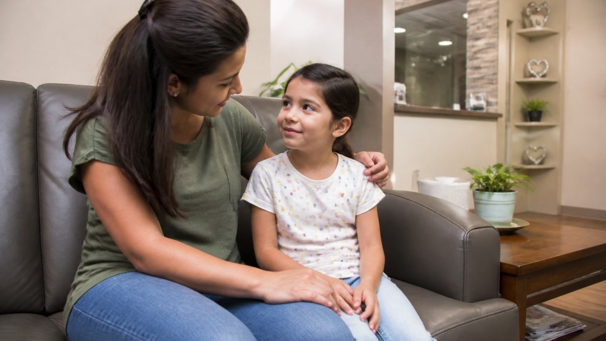 Parent and young child sitting together in a bright, welcoming dental office waiting room, with the child looking calm and the parent reassuring them while they wait for their appointment