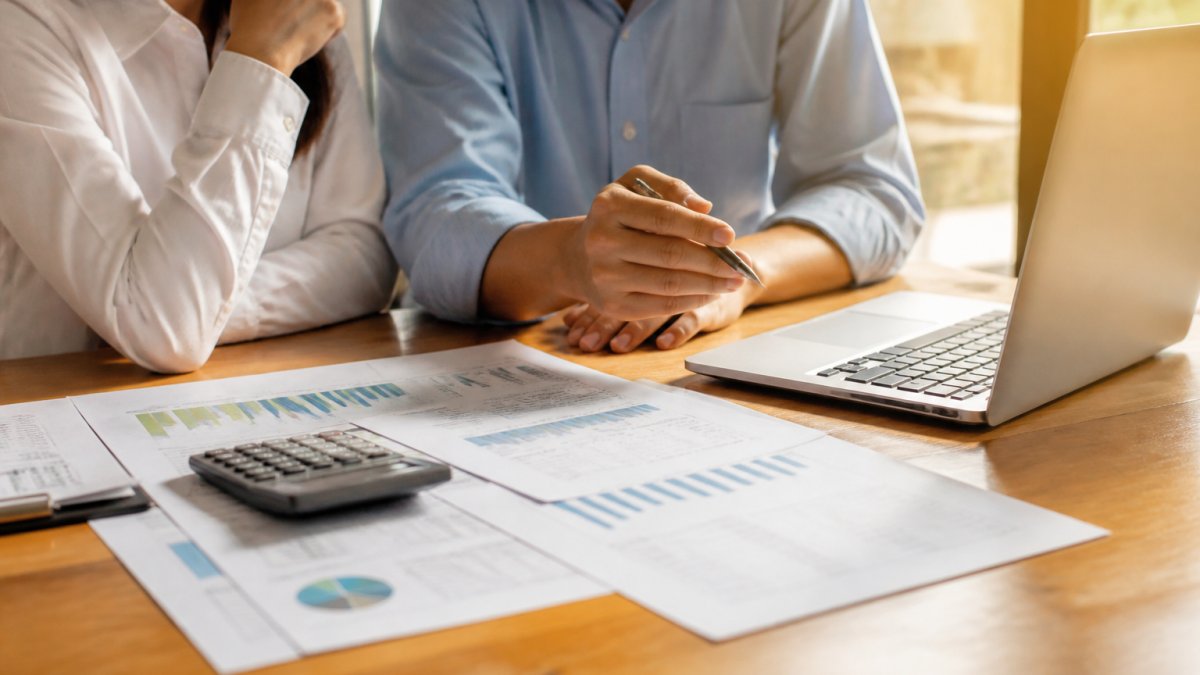 Business owner and financial advisor reviewing growth metrics for fractional CFO services on a laptop