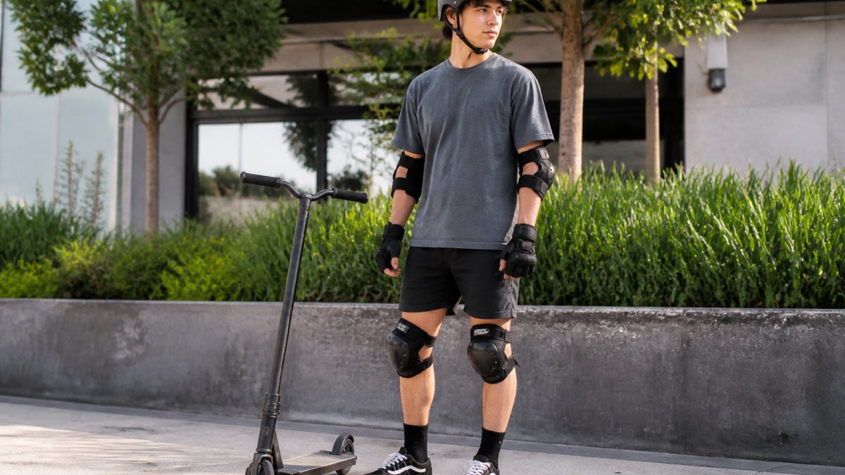 Beginner rider wearing full safety gear and helmet next to their best scooter for beginners in an urban setting
