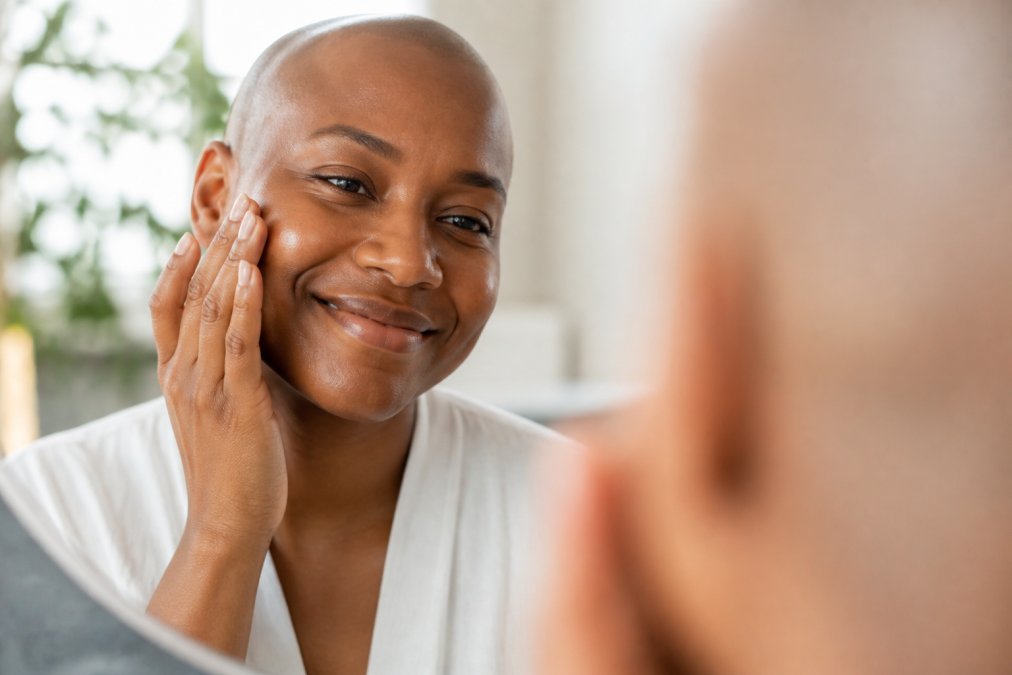 A close-up of a woman's serene face with healthy, glowing skin, gently touching her cheek, soft natural light