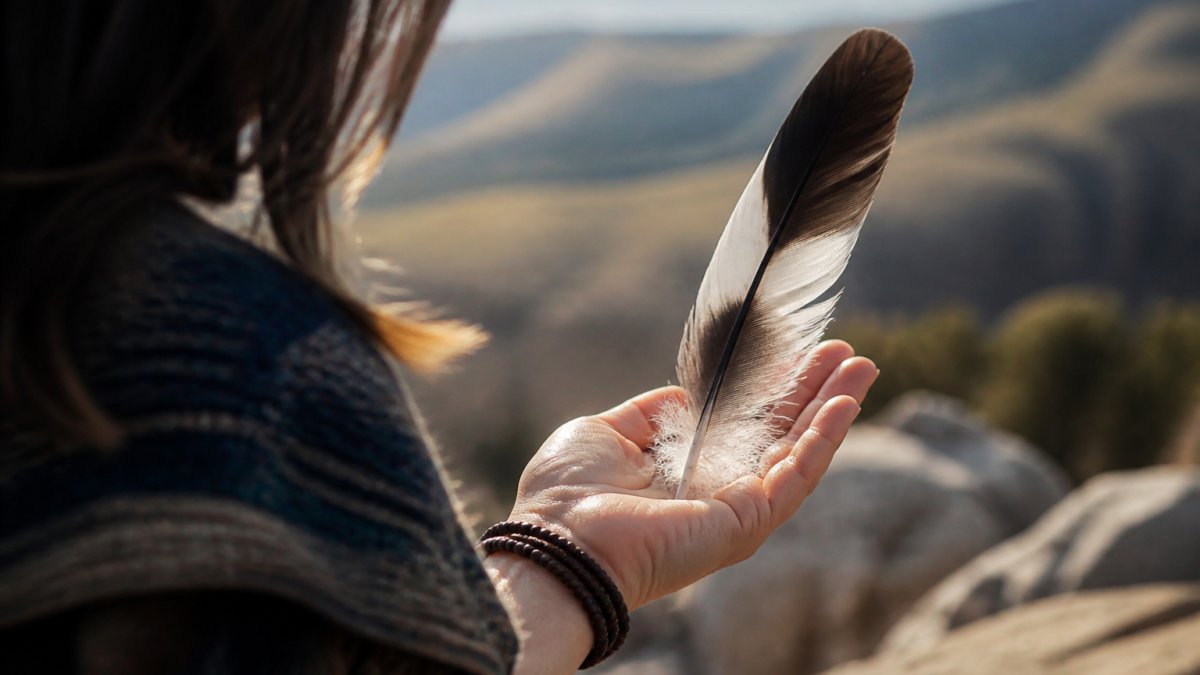 What Feathers Symbolise Spiritually: A Guide to Finding Meaning 1 A person holding a single feather in their hand outdoors, with natural light illuminating the feather's texture and detail, showing a moment of quiet reflection