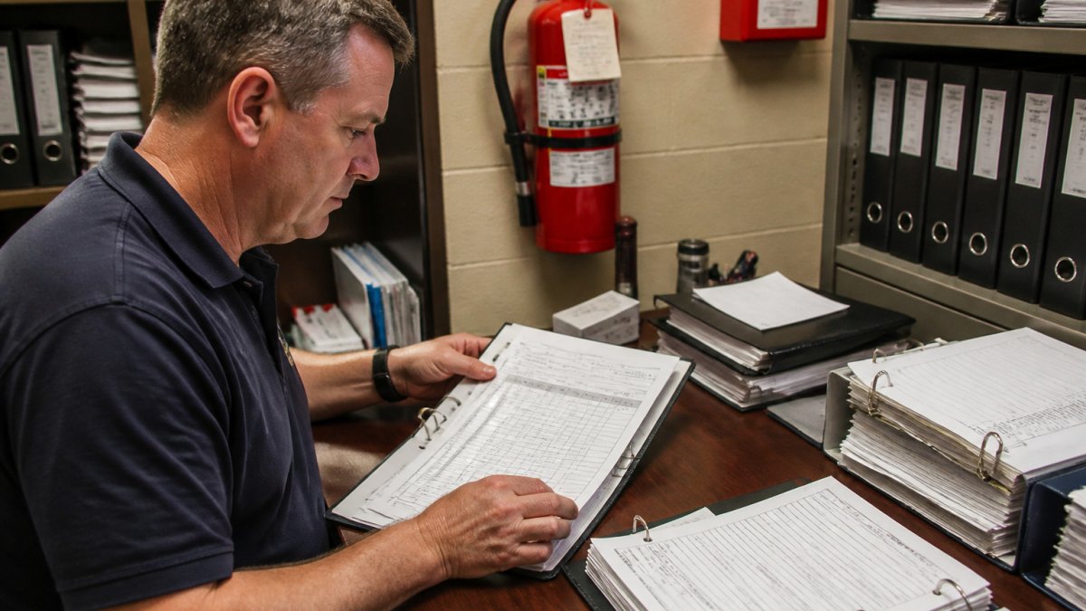 Facility manager reviewing fire extinguisher inspection logs to ensure fire code record retention compliance