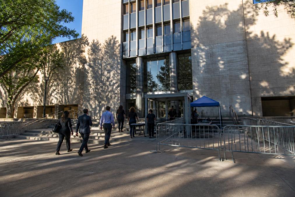 Exterior view of the Van Nuys courthouse building with people entering through the main entrance and security checkpoint area, morning sunlight, professional architecture