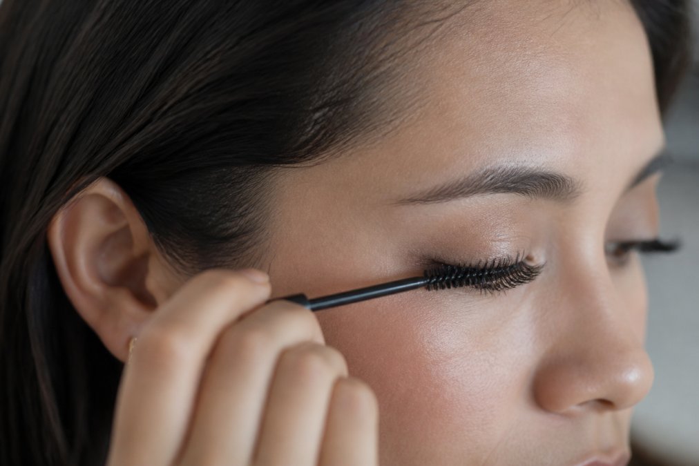 Woman gently using a clean spoolie to brush lash extensions to keep them neat and damage-free