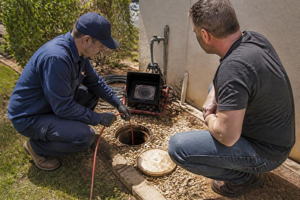 Plumber using a sewer camera to inspect a main line so you do not ignore a slow drain in your home sewer system.