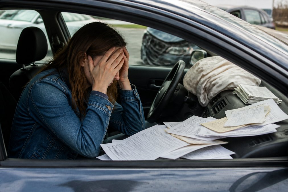 Stressed driver in a wrecked car looking at medical bills due to lacking uninsured motorist coverage