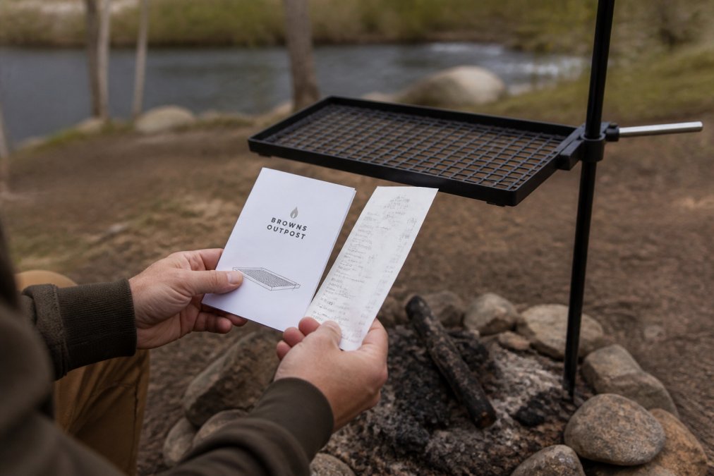 Close-up of hands holding a receipt and product documentation next to a carbon steel grill, showing the proof of purchase materials needed for a warranty claim