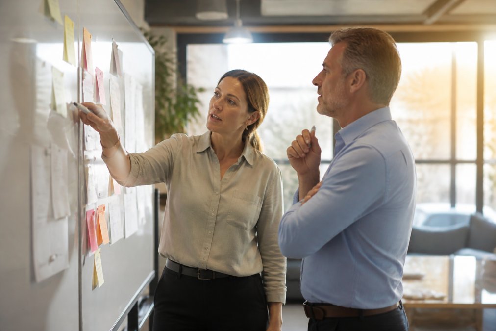 Consultant and owner reviewing a CRM dashboard to improve operational leverage in a sunlit office