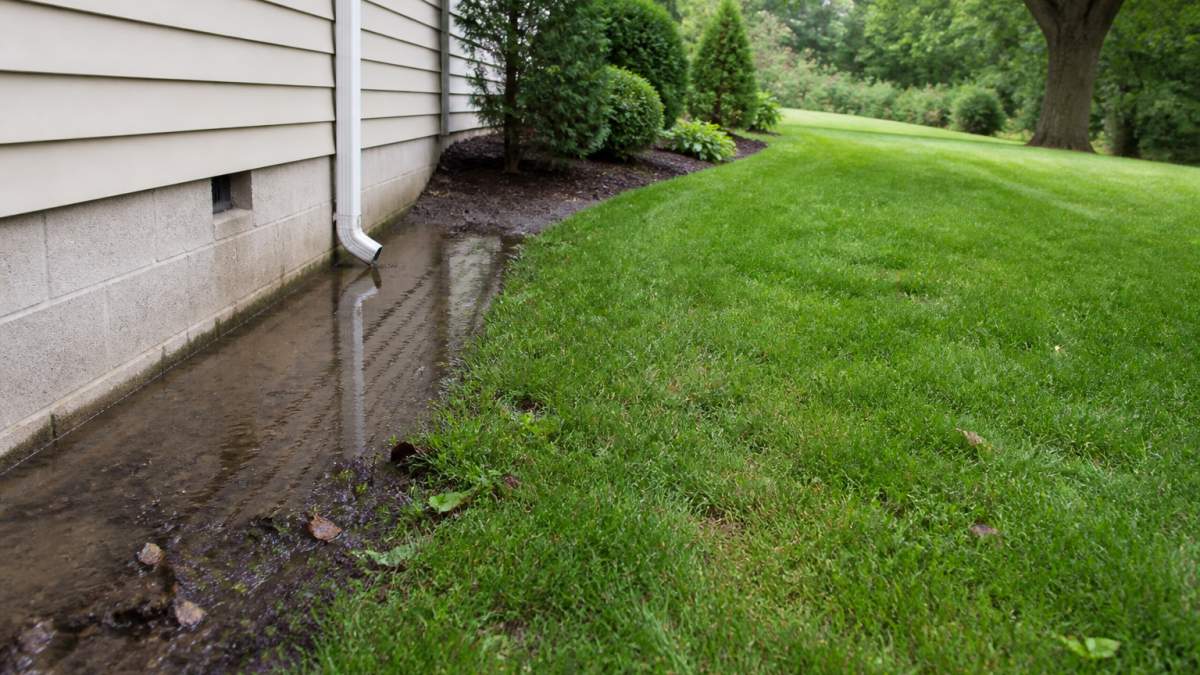 Diagram comparing water pooling near a foundation versus a sloped yard to explain the purpose of land grading.