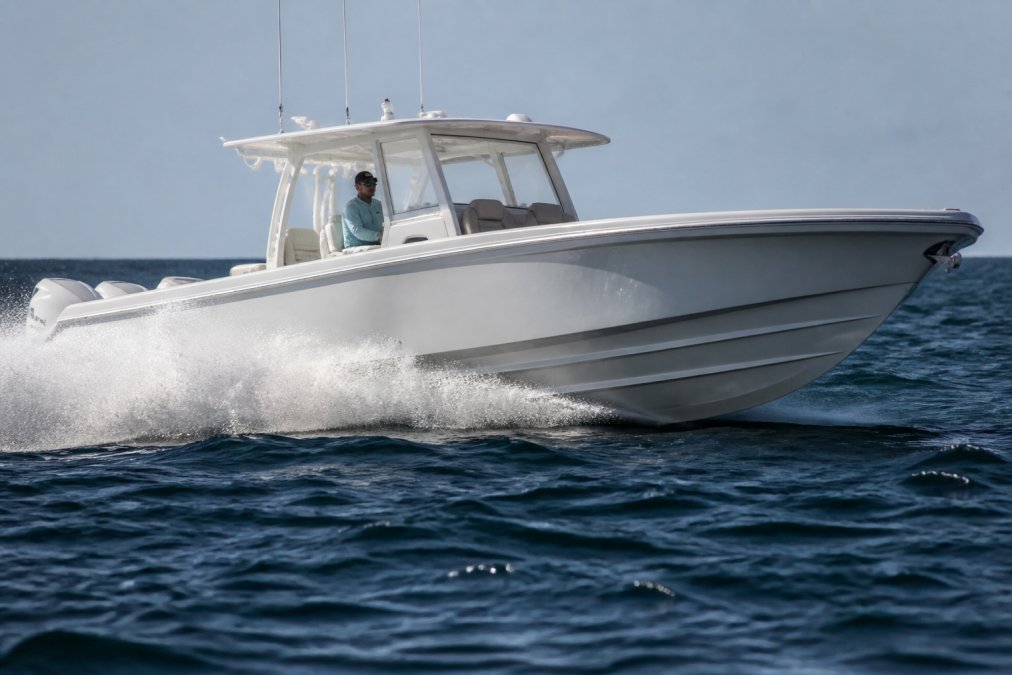 A premium center console yacht cutting through choppy offshore waters, showing its deep-V hull and spray deflection, with a captain at the helm in calm focus