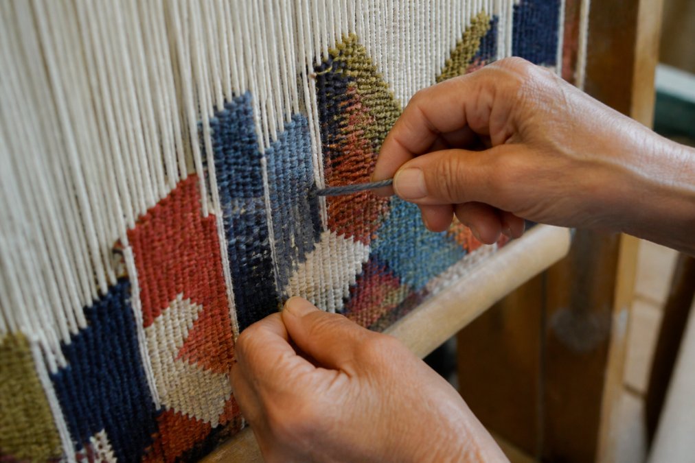 Weaver hands working wool on a loom to create the slit tapestry technique of Anatolian kilims