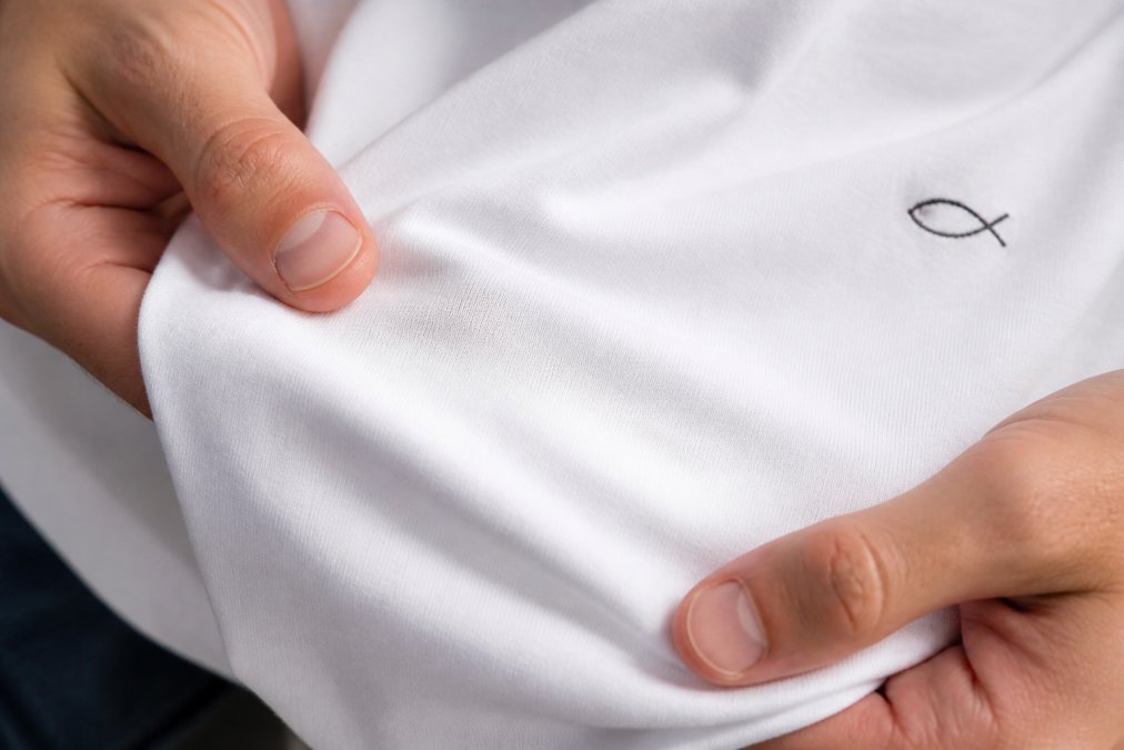 Close-up of premium cotton fabric showing fine weave texture with hands gently touching the material to demonstrate the butter-soft feel and fiber quality