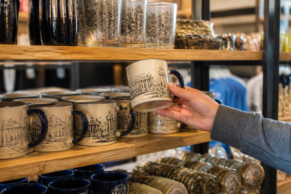 Shopper inspecting the quality of ceramic museum merchandise on a well-lit gift shop display shelf
