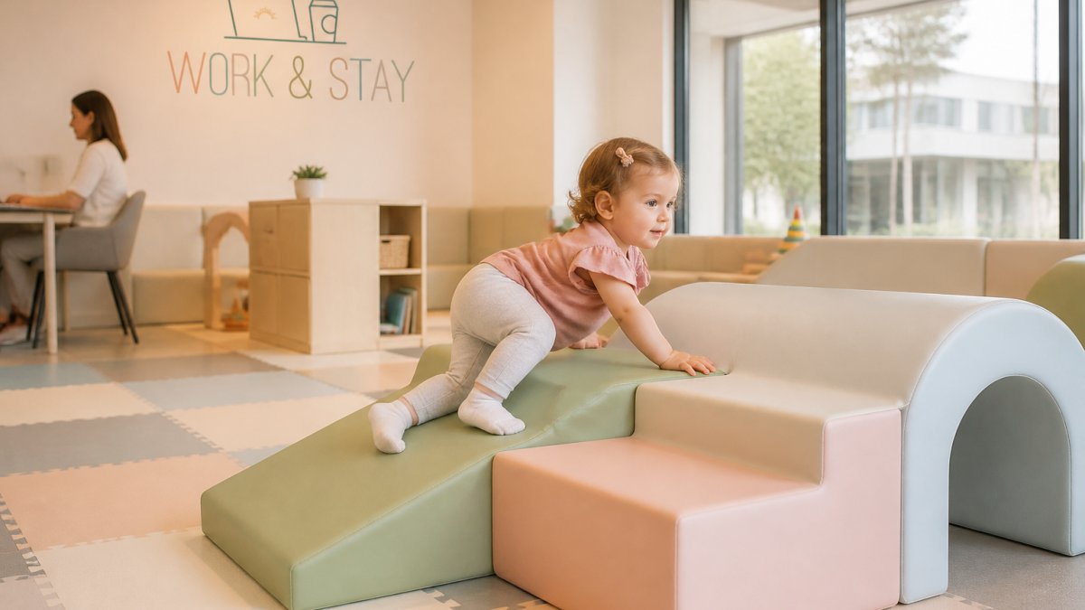 Toddler safely exploring soft climbing structures with rounded edges in a bright, clean play area designed specifically for ages 0-6, with padded flooring visible throughout