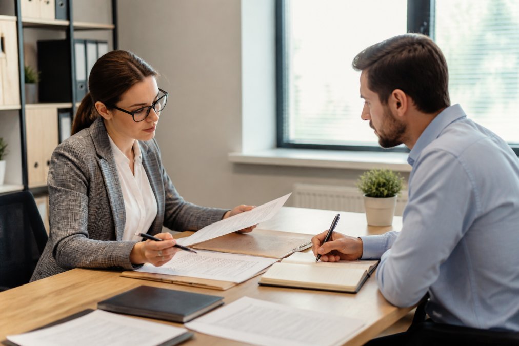A small business owner sitting across a desk from a tax advisor in a bright office, both reviewing documents and taking notes during a consultation