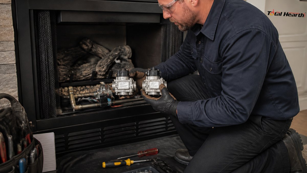 Technician comparing a replacement valve part number to an existing fireplace component during repair
