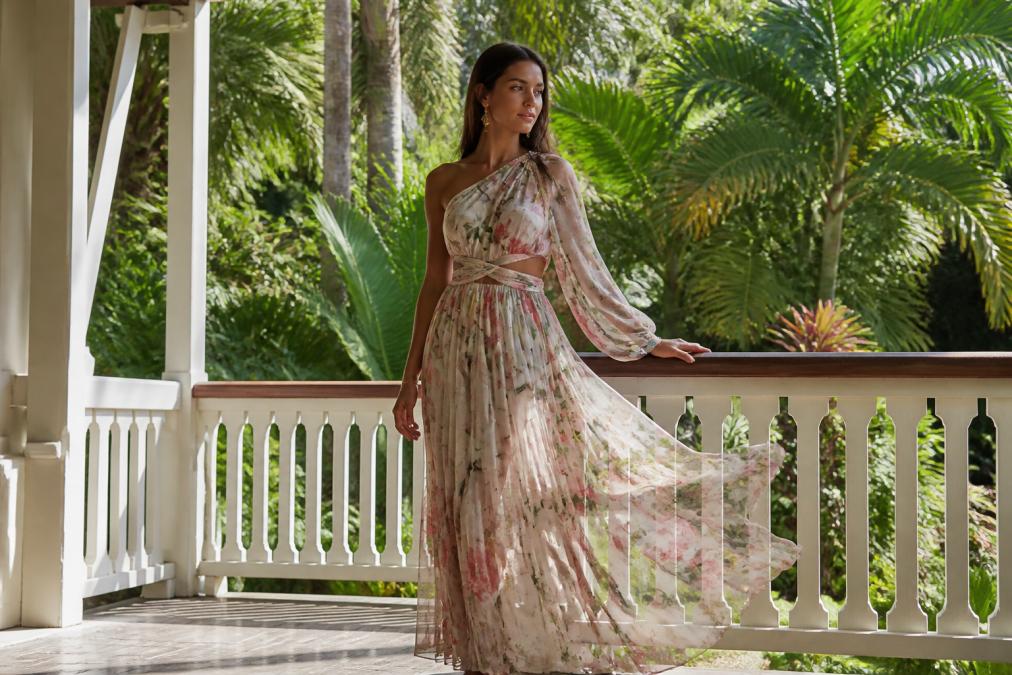 Woman in a flowing floral organza maxi dress standing on a sunlit veranda, perfect for quality formal wear.