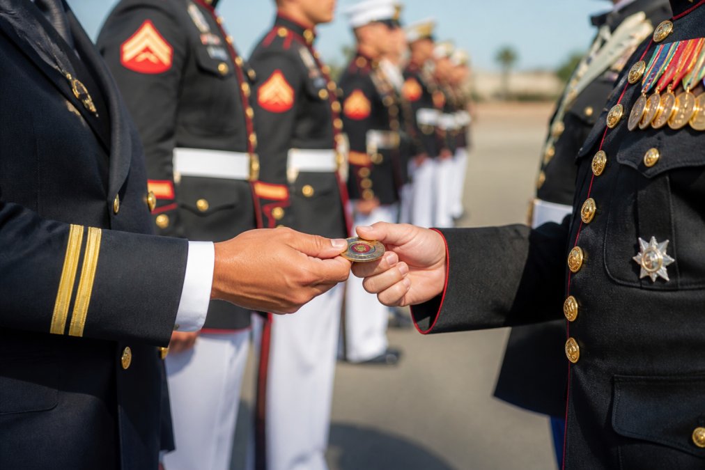 Military service members exchanging challenge coins in a formal setting, demonstrating the tradition and respect associated with unit coins