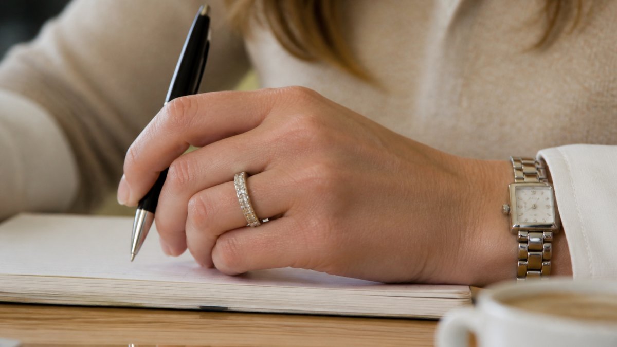 Close-up of a woman's hand wearing a platinum eternity ring during everyday activities, showing the ring's lustrous finish and how it sits on the finger