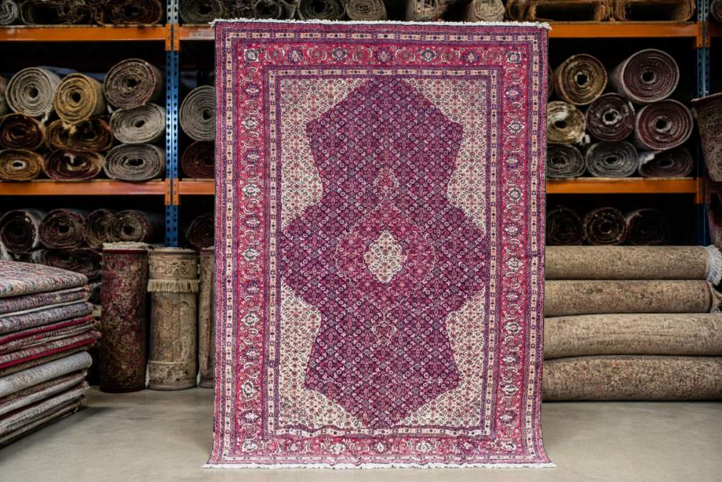 Interior of organized rug warehouse with rolled and stacked rugs on shelving, natural lighting showing scale of wholesale inventory management