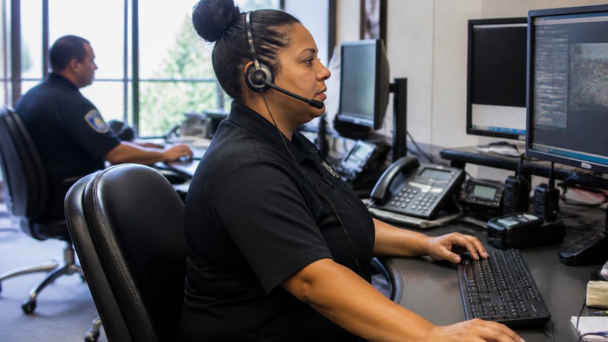 Security dispatcher monitoring screens and coordinating field teams during a live incident response