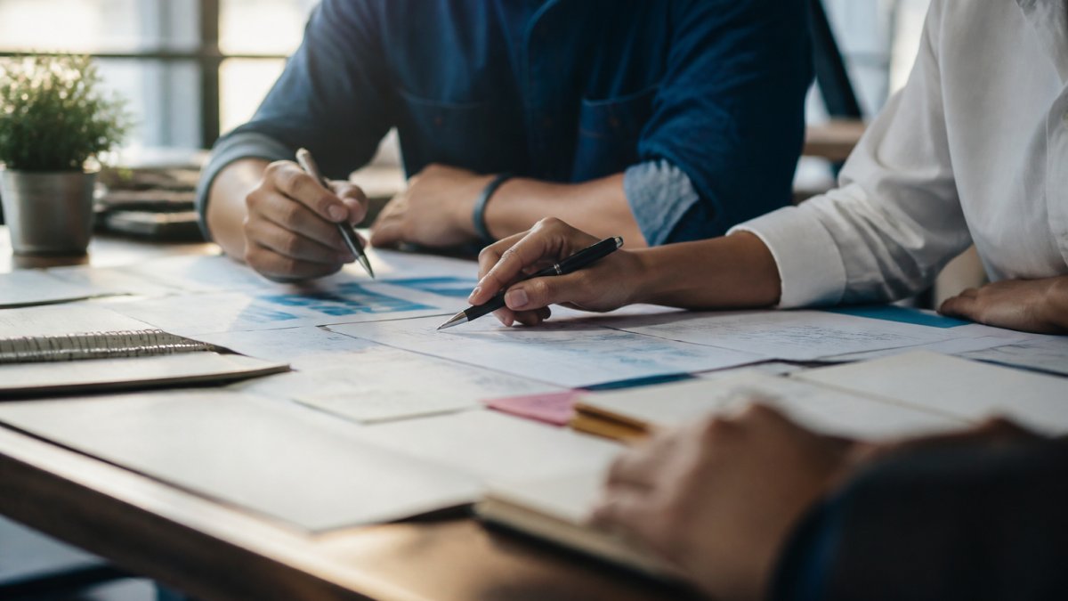 Why Agency Client Onboarding Matters in 2026 Team of agency professionals in a modern office reviewing client documents and strategy notes on a desk, engaged in discussion