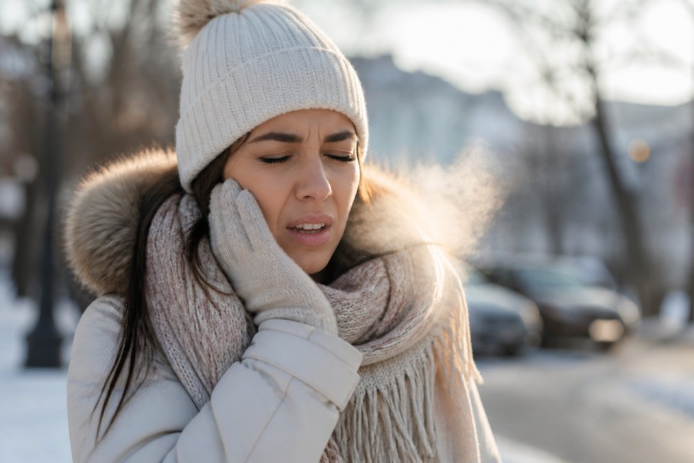 Person wincing while breathing in cold winter air with visible vapor near their cheek