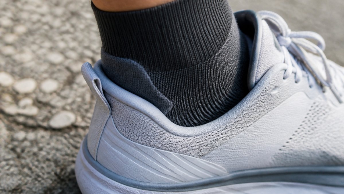 Diagram showing the proper alignment of a sock heel tab within a running shoe to prevent slippage