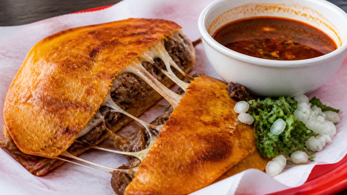 Diagram of authentic quesabirrias showing the crispy tortilla, melted cheese, shredded beef, and savory consomé.