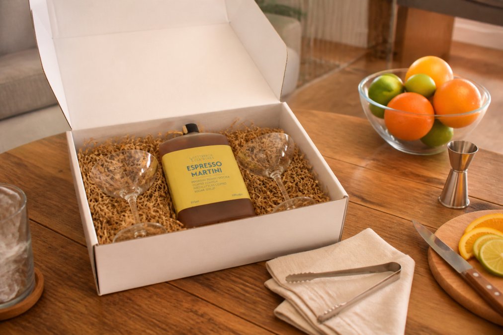 Beautifully packaged premium cocktail gift box opened on a wooden table with chilled glasses, fresh citrus garnishes, and ready-to-drink bottles displayed, showing elegant presentation and ready-to-serve format