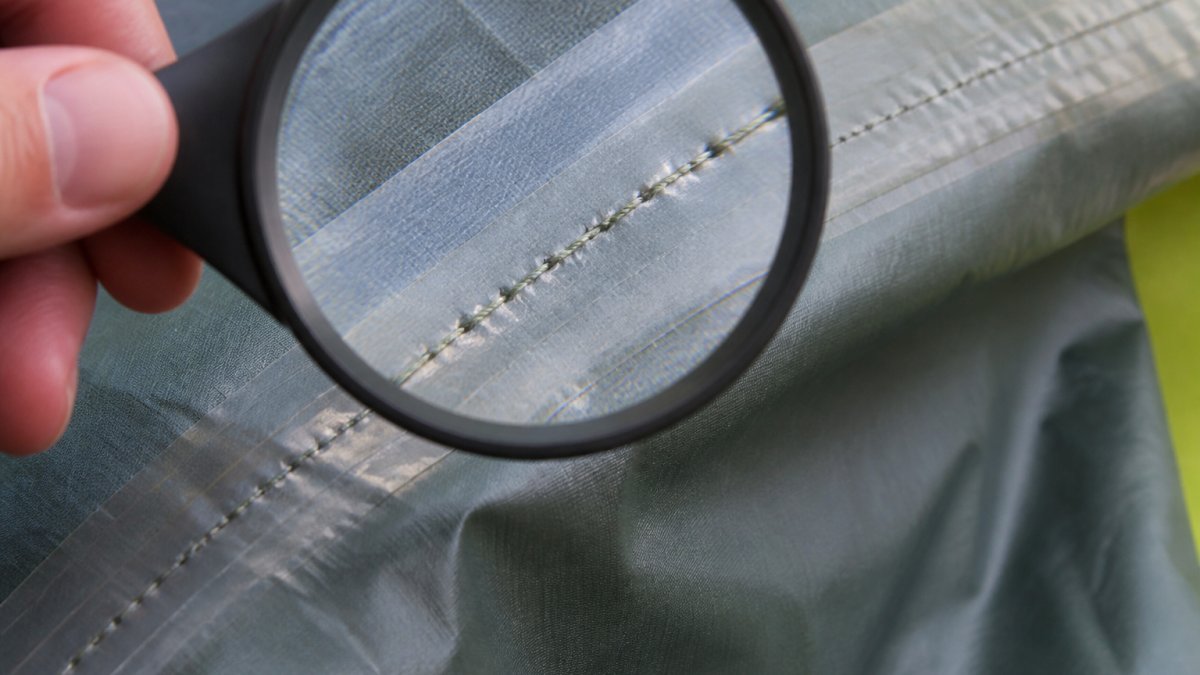 Close-up of tent fabric showing tight, even stitching with reinforced seams and proper seam sealing visible under magnification