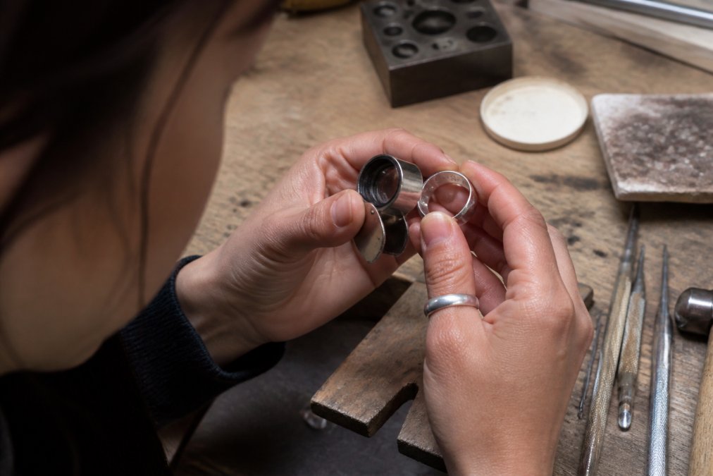 Jeweler examining the hallmark on an artisan silver ring with a loupe