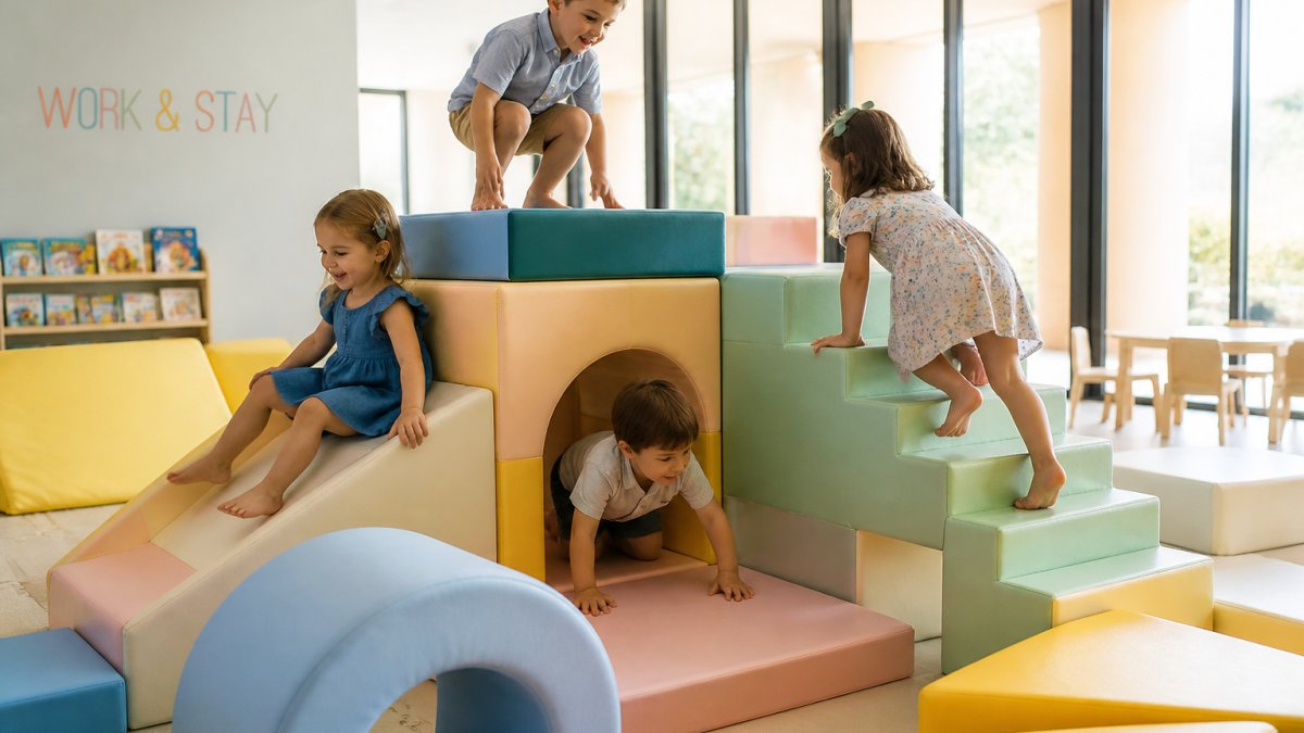 Preschool-aged children playing together on colorful soft play structures and climbing equipment in a bright, clean indoor play space with padded surfaces and natural lighting