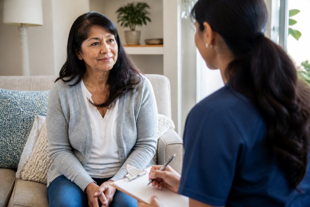 Healthcare provider listens to a patient discussing their chronic pain treatment in a bright, supportive living room.