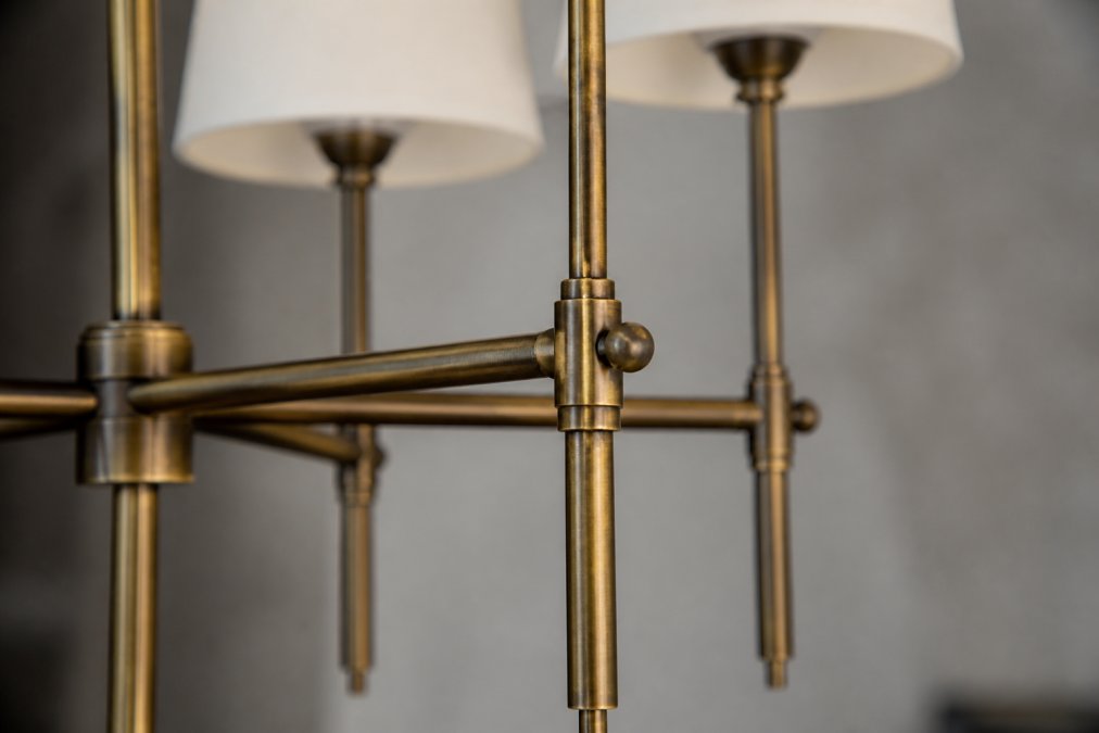 Close-up of hand-finished brass chandelier components showing polished metalwork, detailed joints, and artisanal finishing touches under studio lighting