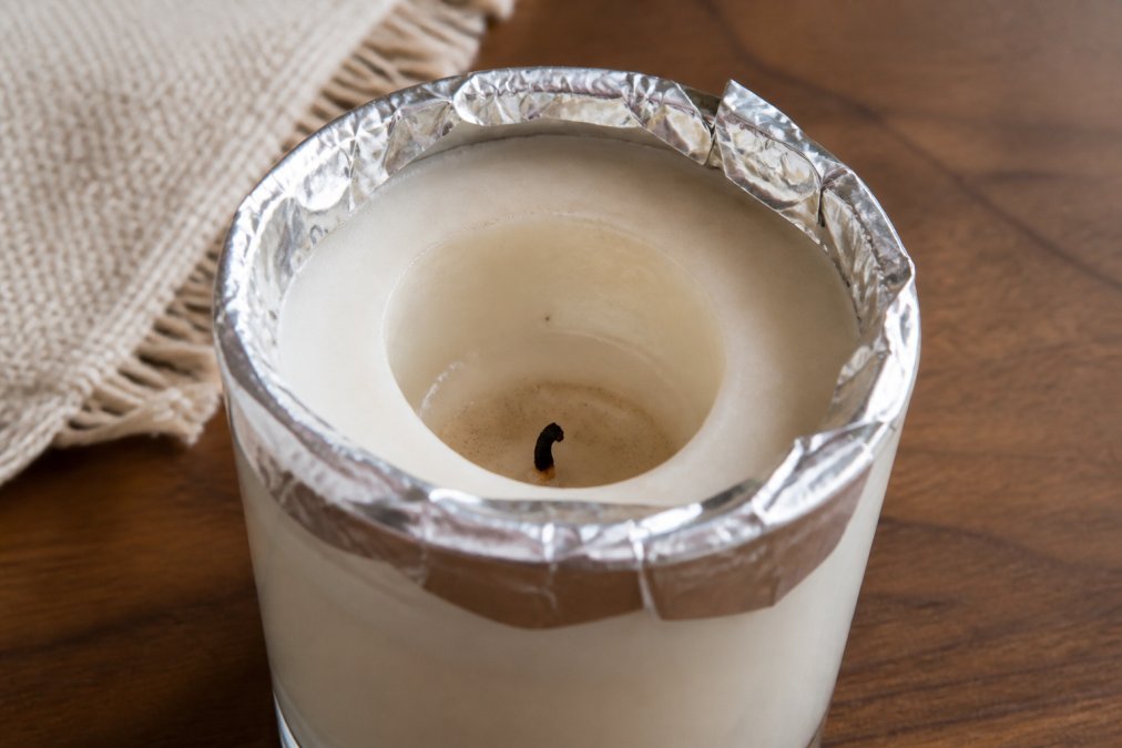 Diagram showing how to use aluminum foil to fix a candles tunnel by reflecting heat toward the wax edges.