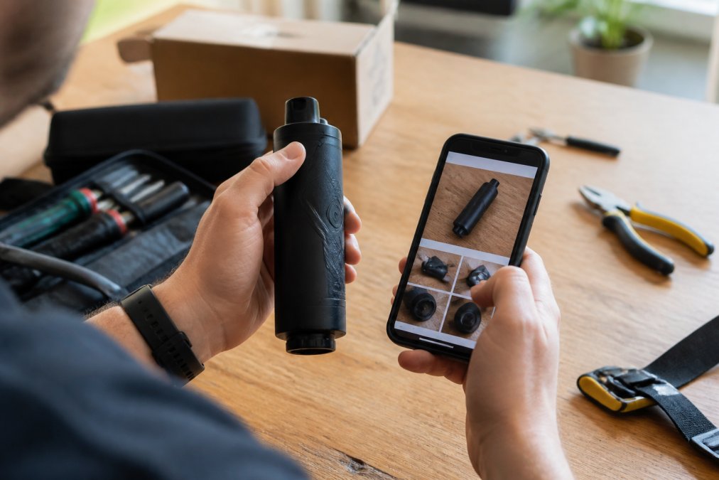 Close-up of hands holding a product while reviewing details on a smartphone screen, examining specifications and customer photos in natural daylight