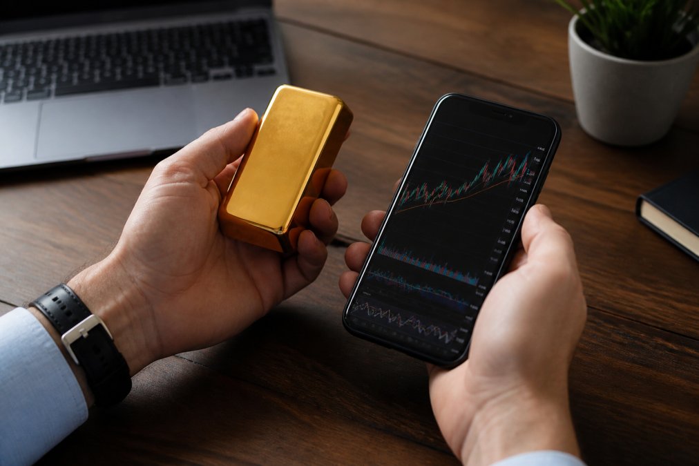 Hands holding a gold bar beside a smartphone crypto chart in the gold digital age investment comparison.