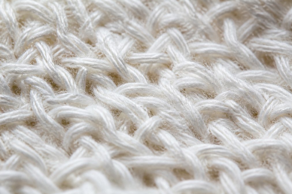 Close-up of white cotton fabric fibers showing detailed textile weave structure and individual fiber strands under natural light