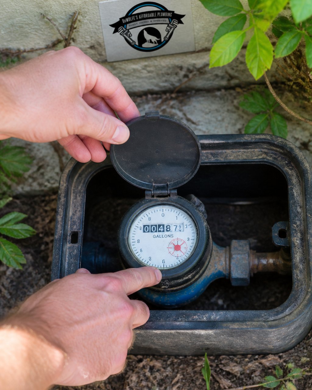 Close-up of hands checking a residential water meter to identify leaks causing a water bill so high