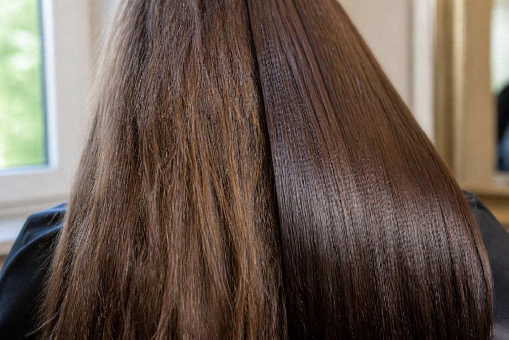Close-up of damaged hair strands showing frizz and dull texture contrasted with smooth, shiny keratin-treated hair under natural window lighting