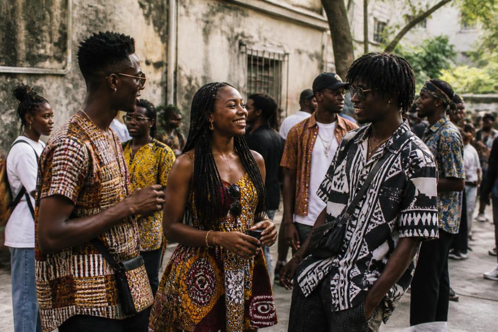 Young adults wearing bold graphic streetwear with confident posture and expressive body language at a cultural gathering, celebrating their heritage through their apparel choices with natural outdoor lighting